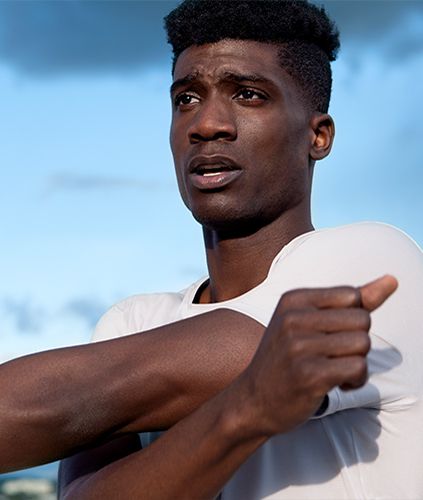 Man stretching his arm across his body wearing Fast and Free short sleeve.
