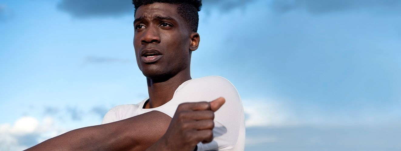 Man stretching his arm across his body wearing the Fast and Free short sleeve.