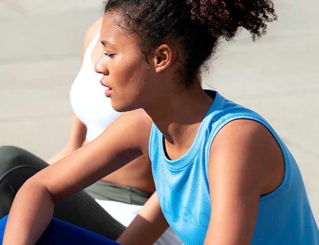 Woman wearing Breeze By Muscle Shirt sitting next to a woman wearing the Enlite bra.